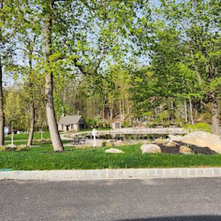 A peaceful park scene with lush greenery and a wooden bridge.