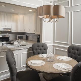 A modern kitchen and dining area featuring a round table with place settings, plush chairs, and a stylish chandelier.