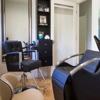 A modern hair salon with comfortable chairs and a large mirror.