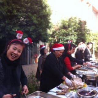 People celebrating outdoors with festive attire and cooking stations.