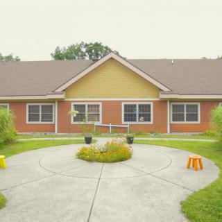 A brick building with a landscaped garden and circular walkway in front.