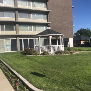 A well-maintained lawn with a gazebo in front of a multi-story building.