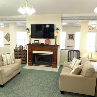 A cozy living room with two beige sofas facing a fireplace and a mounted television.