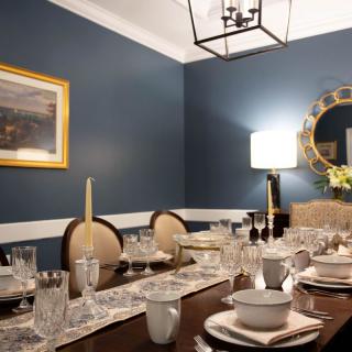 An elegantly set dining table in a room with blue walls, featuring a chandelier and decorative elements.
