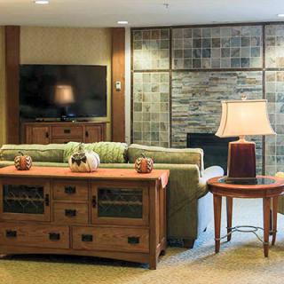 A cozy living room with a couch, wooden furniture, and a television mounted on the wall.