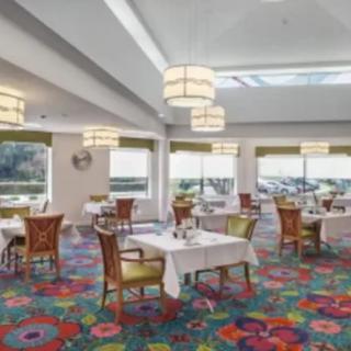 A brightly lit restaurant interior with colorful carpet and neatly arranged tables and chairs.