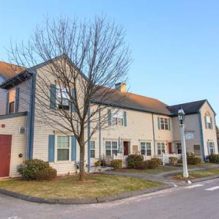 A suburban residential house with a well-maintained exterior and a leafless tree in the front yard during the day.