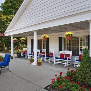 A charming porch with rocking chairs and hanging plants creates a cozy outdoor seating area.