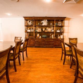 A dining room with a long table, chairs, and a wooden cabinet against the wall.