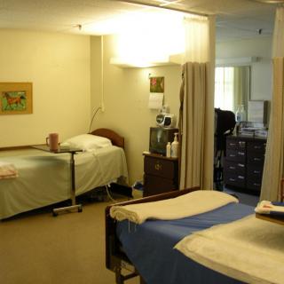 A hospital room with two beds separated by a curtain, featuring medical equipment and supplies.