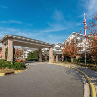 The image shows the entrance to a residential building with a driveway and landscaping.