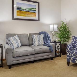 A cozy living room setup featuring a gray sofa with patterned pillows, side tables with lamps, and a decorative plant.
