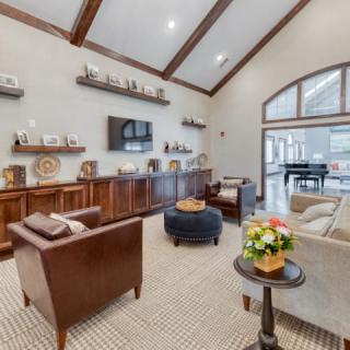 A cozy living room with high ceilings and wooden furniture, featuring a seating area and decorative shelves.