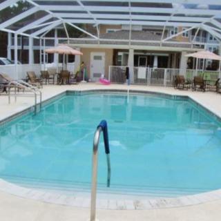 An enclosed outdoor swimming pool with patio furniture surrounding it.