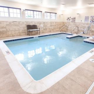 An indoor swimming pool with tiled edges and a seating area.
