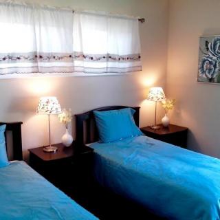 A cozy bedroom with twin beds and blue bedding, featuring nightstands and lamps.
