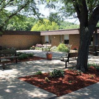 A serene outdoor garden area featuring benches, pathways, and lush greenery.