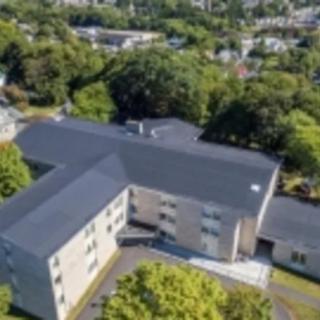 Aerial view of a residential building surrounded by trees in an urban area.
