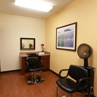 A cozy hair salon room with a styling chair, mirror, and a hair dryer station.