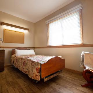 A cozy and minimalistic bedroom featuring a single bed, natural light from the window, and simple furnishings.