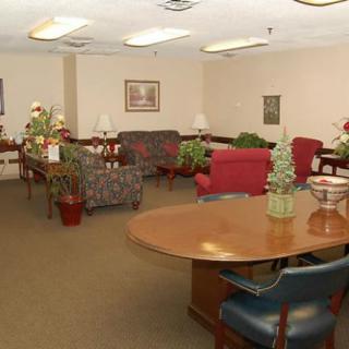 A lobby area with chairs, tables, and decorative plants.