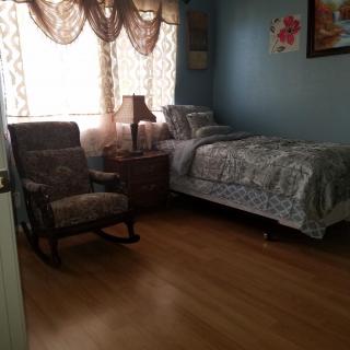 A cozy bedroom with a single bed, rocking chair, and decorative curtains.