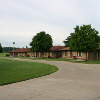 A roadside motel with a curved driveway lined by trees.