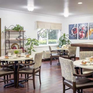 A cozy dining area with neatly arranged tables and chairs, decorated with plants and wall art.
