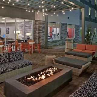 A cozy outdoor seating area featuring a fire pit, modern furniture, and ambient string lights.