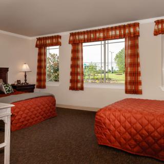 A cozy hotel room with twin beds, adorned with orange bedding and matching curtains.