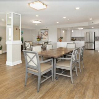 A modern dining area with a wooden table and chairs, adjacent to a sleek kitchen.