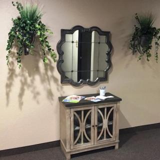 A decorative console table with a mirror and wall-mounted plants.