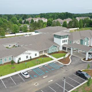 Aerial view of a large building with a parking lot and surrounding greenery.
