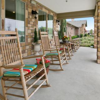 A row of wooden rocking chairs on a cozy porch, offering a relaxing outdoor seating area.