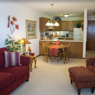 Cozy living space with an open kitchen and dining area, featuring comfortable furniture and warm decor.