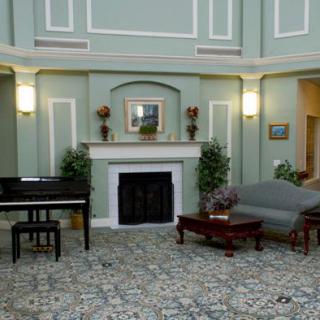 A spacious living room with elegant decor, featuring a fireplace, piano, sofa, and coffee table.