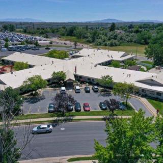 Aerial view of a building with a parking lot surrounded by trees and a road.