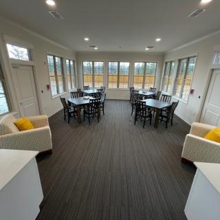 A spacious meeting room with several tables and chairs, surrounded by large windows.