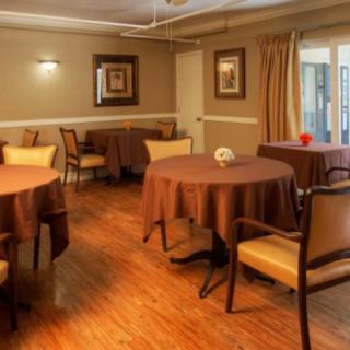 A cozy dining room with round tables and chairs, featuring wood flooring and warm lighting.