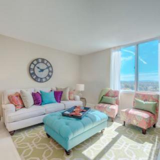 A bright and colorful living room with a comfortable sofa, chairs, and a stylish ottoman.