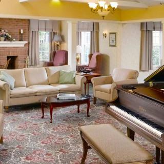 A cozy living room featuring a grand piano, comfortable sofas, and elegant decor.