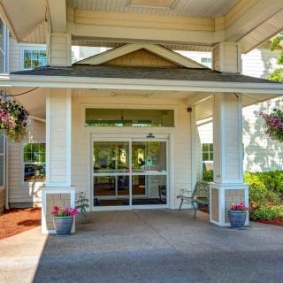 A welcoming entrance to a residential or commercial building, featuring a covered porch and surrounding greenery.