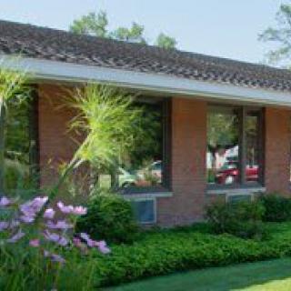 A brick building surrounded by lush greenery and flowers.