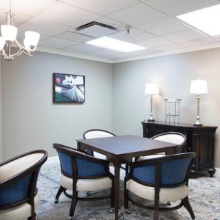 A well-lit meeting room with a conference table surrounded by four chairs, decorated with modern artwork and ambient lighting.