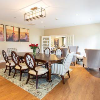 A modern dining room with a large wooden table, elegant chairs, and stylish artwork on the wall.