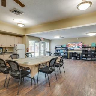 A spacious community room with tables, chairs, and a kitchen area, suitable for meetings and gatherings.