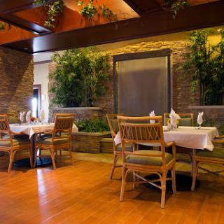 A serene dining area featuring wooden decor and lush greenery.