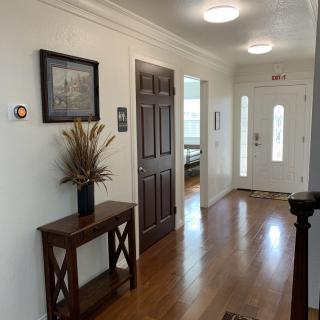 A well-lit hallway with a wooden console table, picture frame, and doors leading to other rooms.