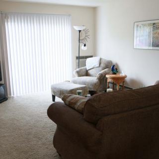 A cozy living room with a sofa, armchair, and television.