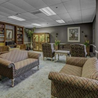 A cozy office lounge with sofas, armchairs, and bookshelves.